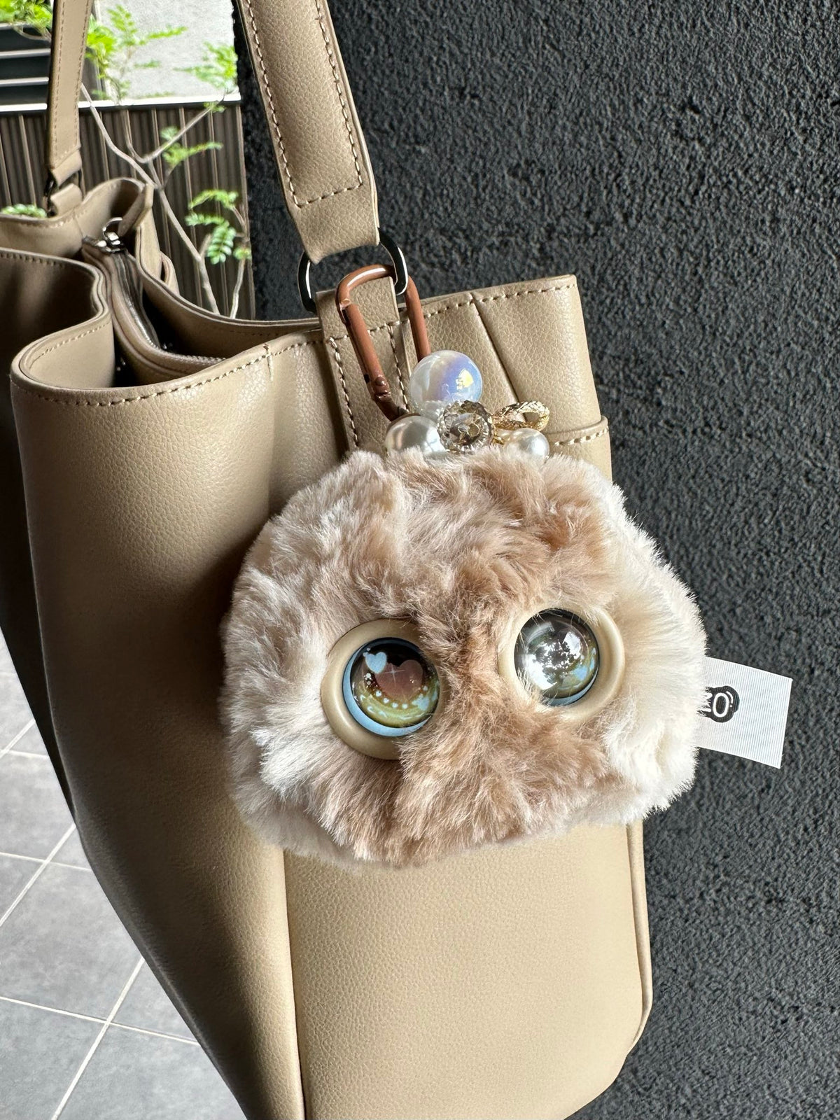 Beige Fuzozo hanging from a handbag