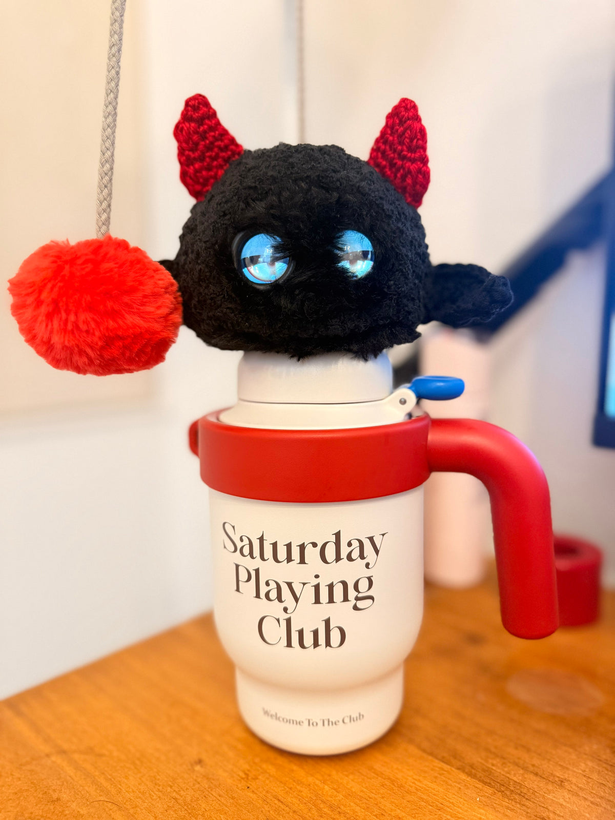Black Fuzozo with red horns sitting on a travel cup