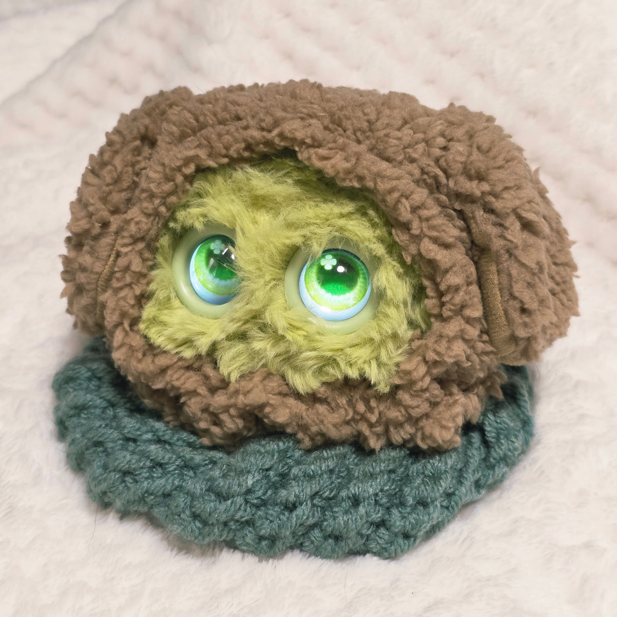 Green Fuzozo wearing a brown fluffy hood